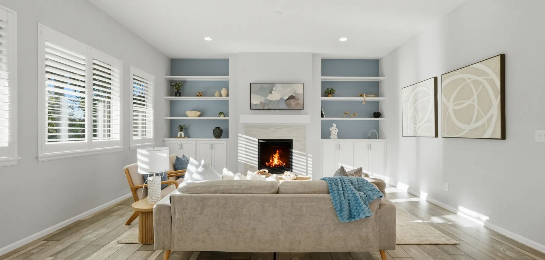 Staged living room with built-in shelves, a fireplace and a cream sofa